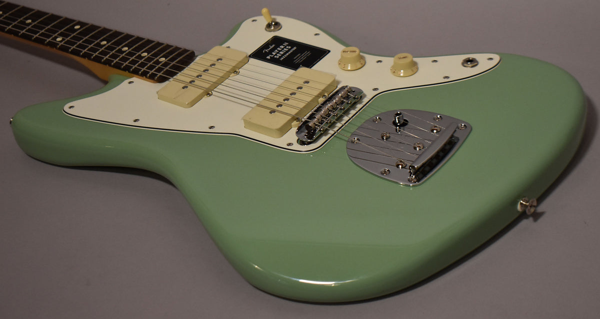 The Birch Green Jazzmaster body, with a white pickguard, two cream pickups, and chrome bridge, is angled from the upper left.