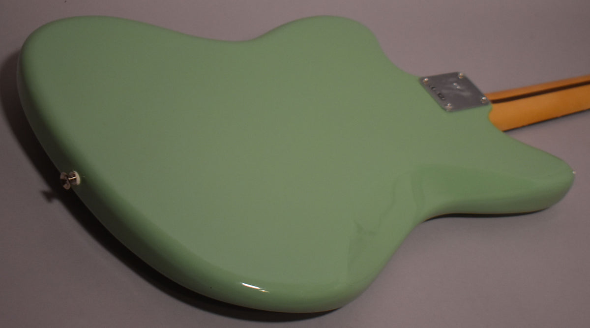 The back of a glossy Birch Green Jazzmaster body, angled from the lower left, with a chrome neck plate and maple neck visible at the top right.