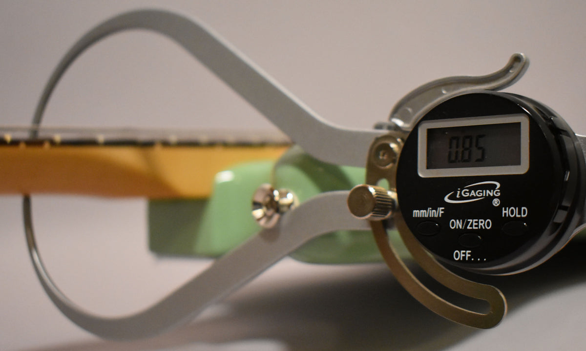 A digital caliper measures the neck thickness of the Birch Green Jazzmaster, displaying "0.85" on its screen.