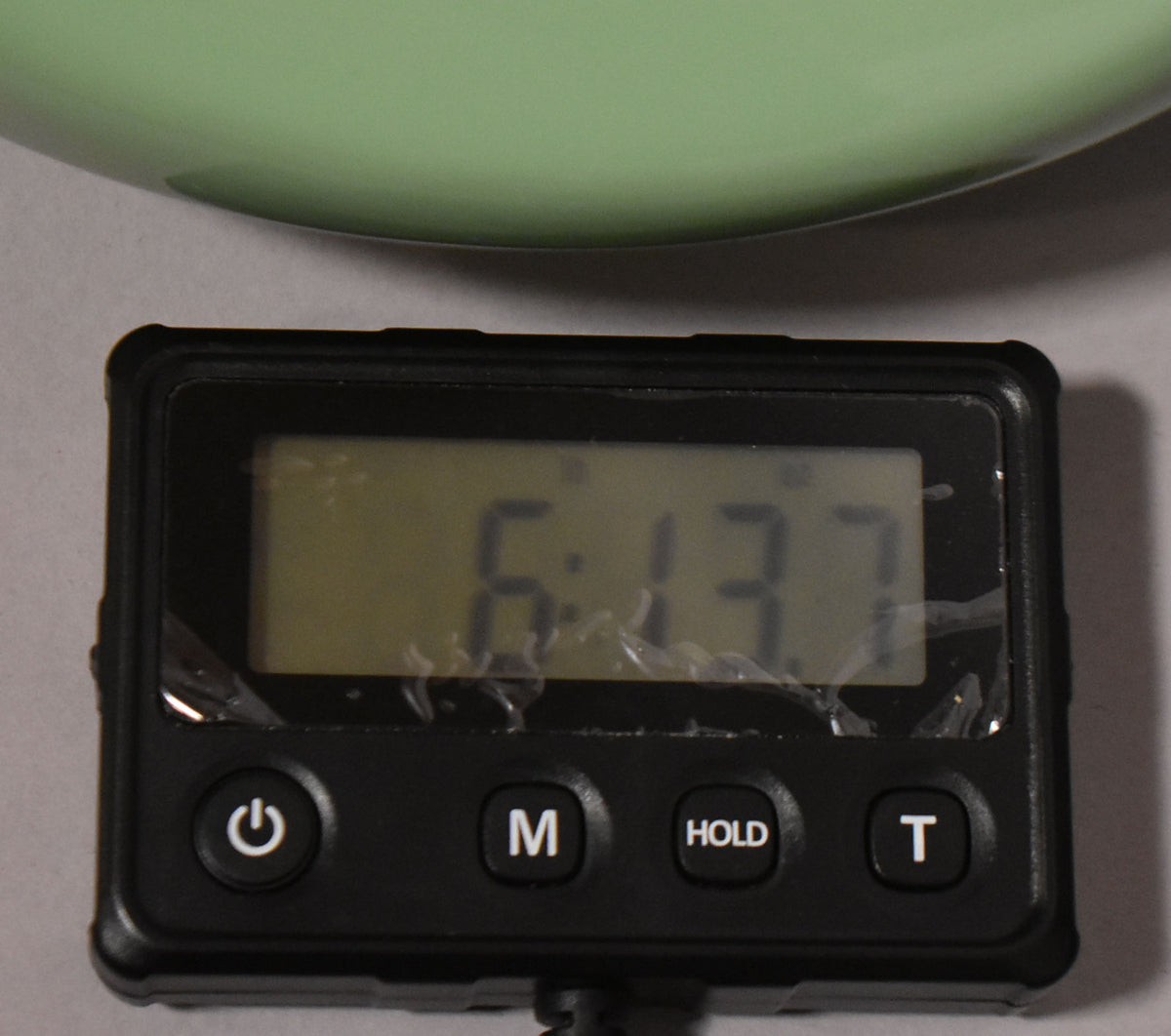 Close-up of a digital scale displaying "6.13" with a light green guitar body partially visible at the top.