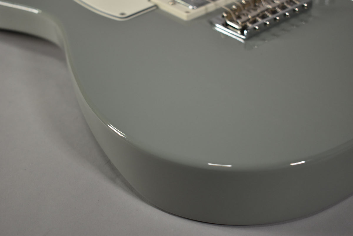 Close-up of the Telecaster's Cactus Gray body, showing the glossy finish and the edge of a white pickguard and chrome bridge.