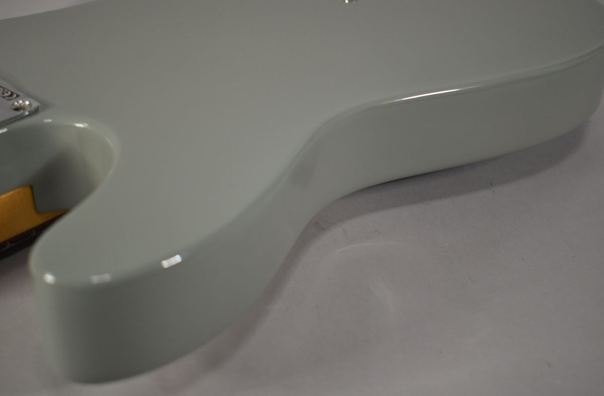 The guitar's lower body, in glossy cactus gray, is angled from the upper left, showing its smooth contours and a hint of the neck joint.