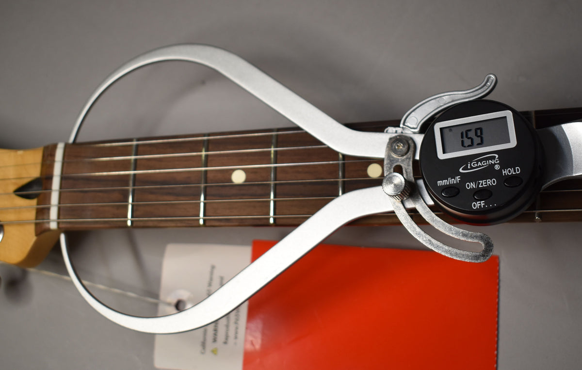 Close-up of a digital caliper measuring the fret height on the guitar's dark rosewood fretboard, displaying "1.59".