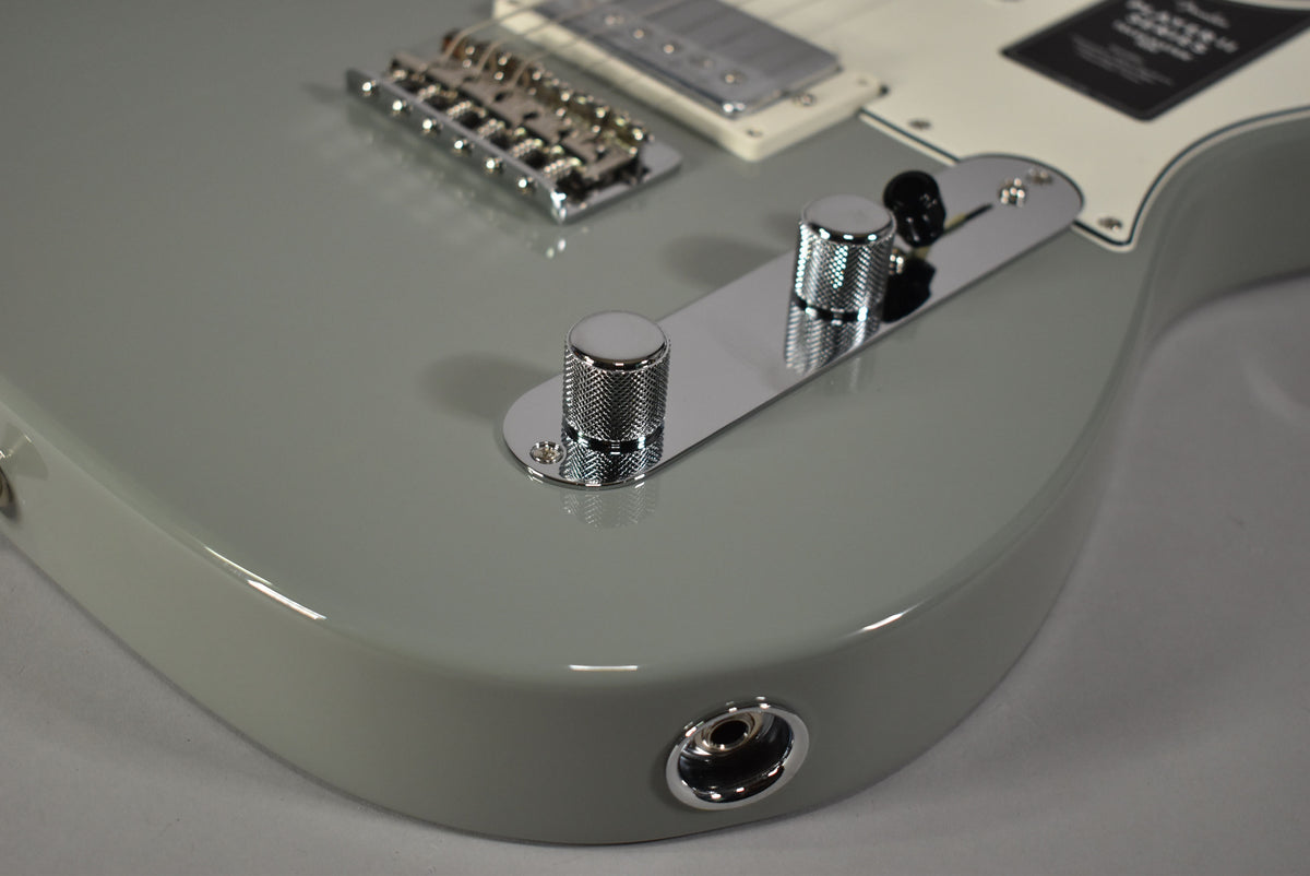 Close-up of the Cactus Gray Telecaster's lower body, showing the shiny chrome control plate with two knurled knobs and the output jack.