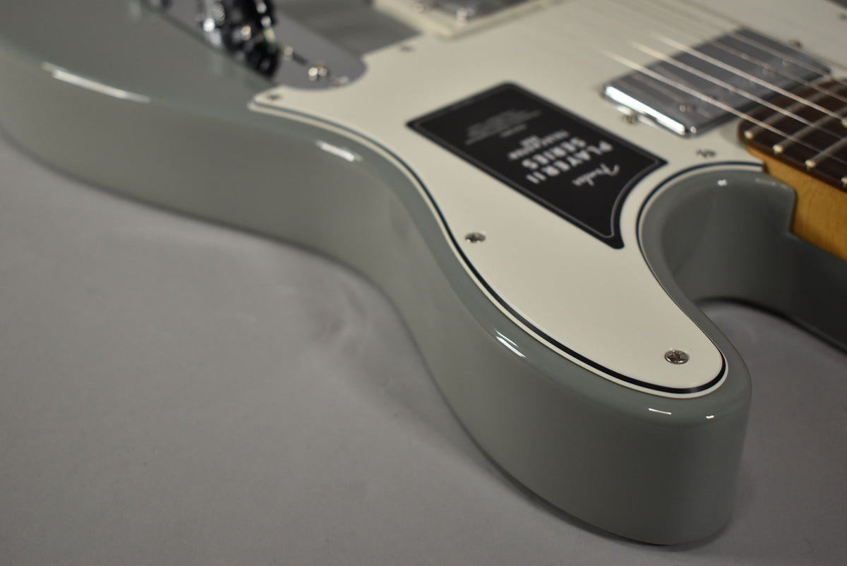 Close-up of the lower bout of a glossy Cactus Gray Telecaster, showing the white pickguard with a black border.