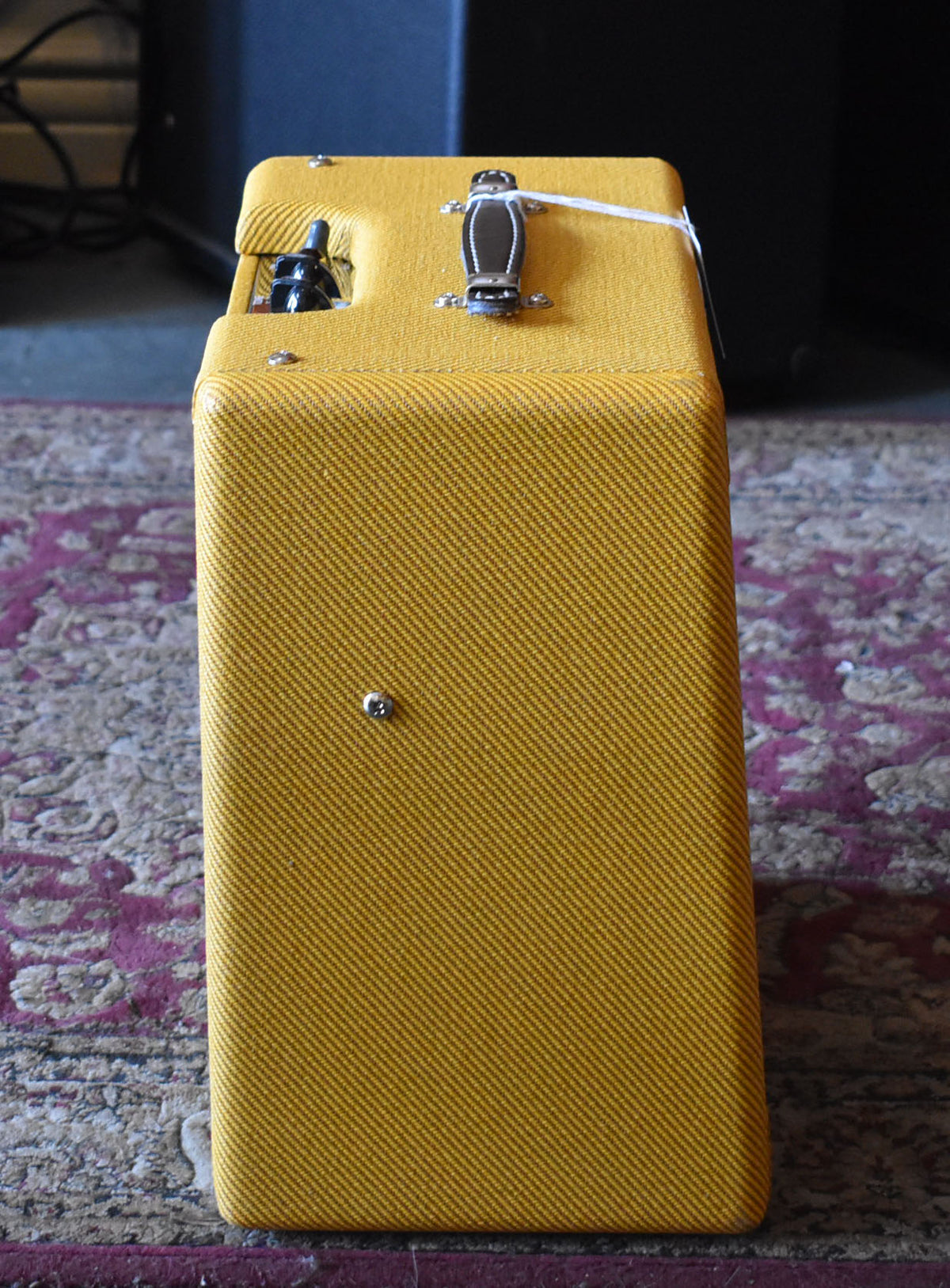 This top-down view shows the tweed amp's textured yellow fabric, black leather handle, and a single black control knob.