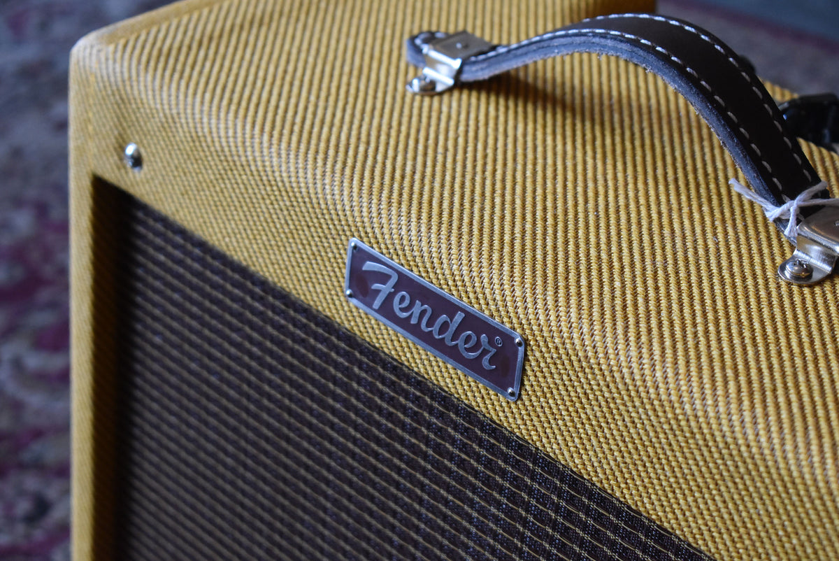 Close-up of the amp's upper right, showing the tweed covering, brown grille cloth, black leather handle, and silver Fender logo.