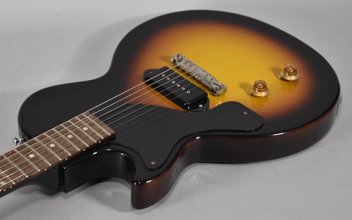 The sunburst single-cut guitar body is angled, showing the black pickguard, single P90 pickup, two amber knobs, and tune-o-matic bridge.