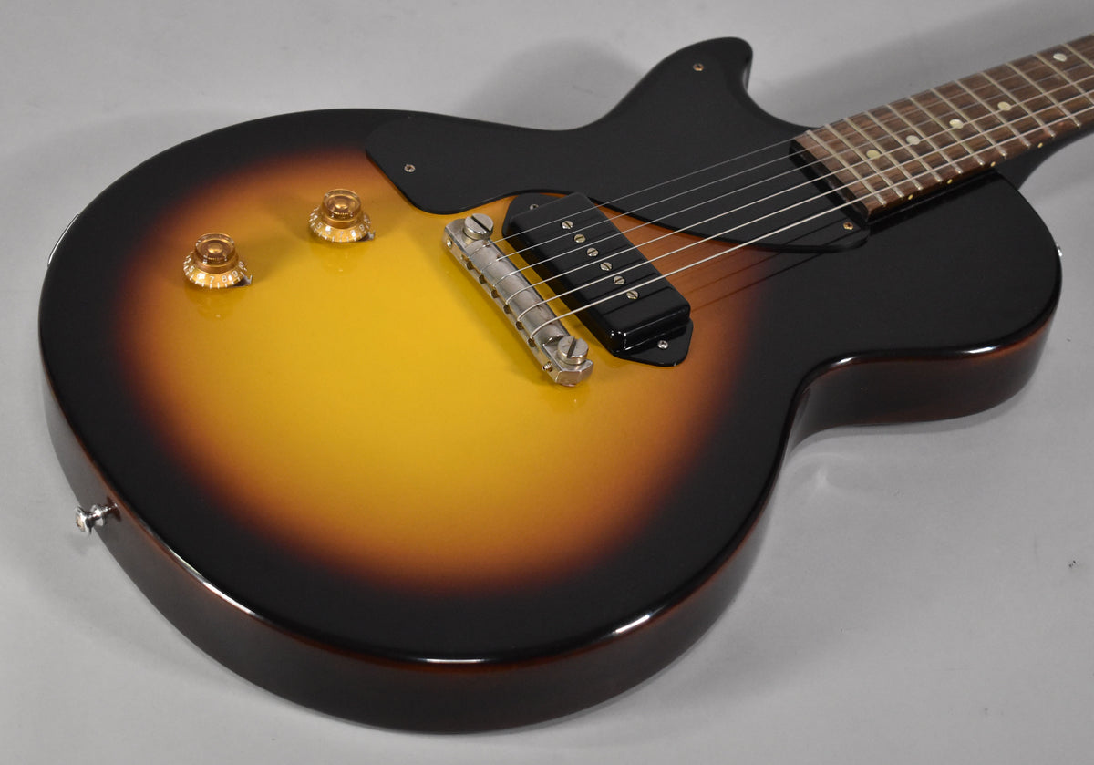 Upper body of a sunburst electric guitar with a black pickguard, P90 pickup, and two amber control knobs.