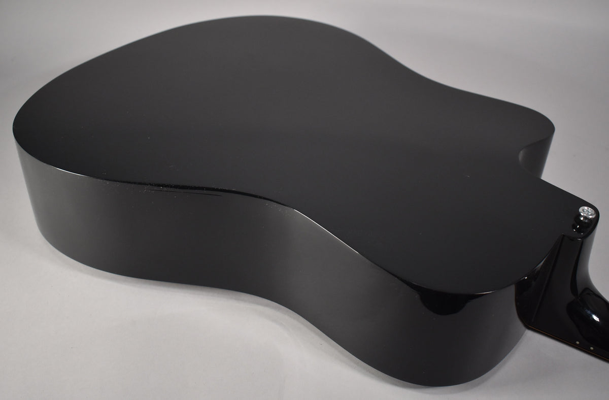 The guitar's glossy ebony back and sides are visible from a high angle, with a slight scuff on the upper bout.
