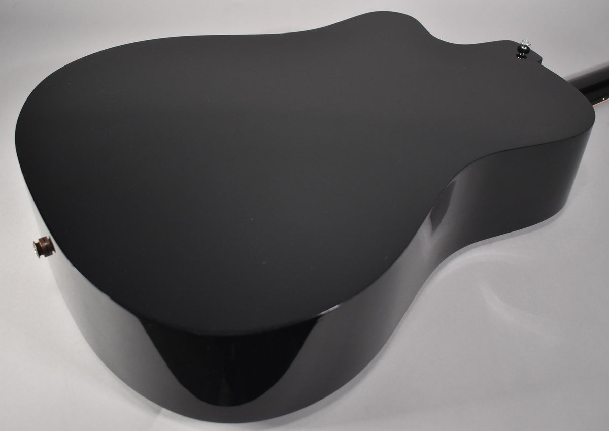 The back of a black acoustic guitar with a matte finish top and glossy sides, viewed from the lower bout.