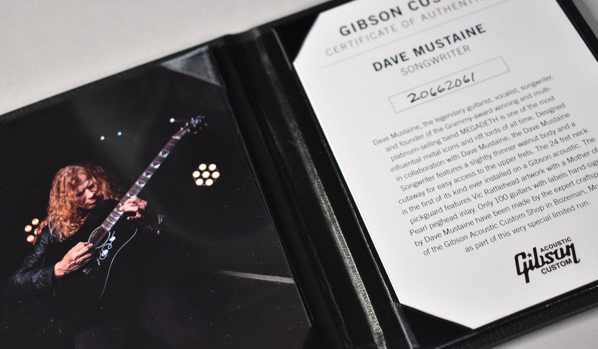 A black leather folder holds a Certificate of Authenticity and a glossy photo of Dave Mustaine playing an ebony acoustic guitar.