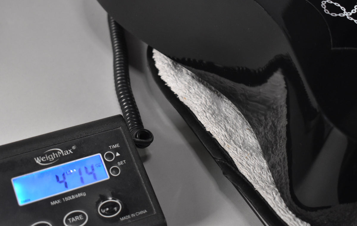 The guitar's weight is displayed as 4 lbs 14 oz on a digital scale, with the shiny black body resting in its white plush-lined case.
