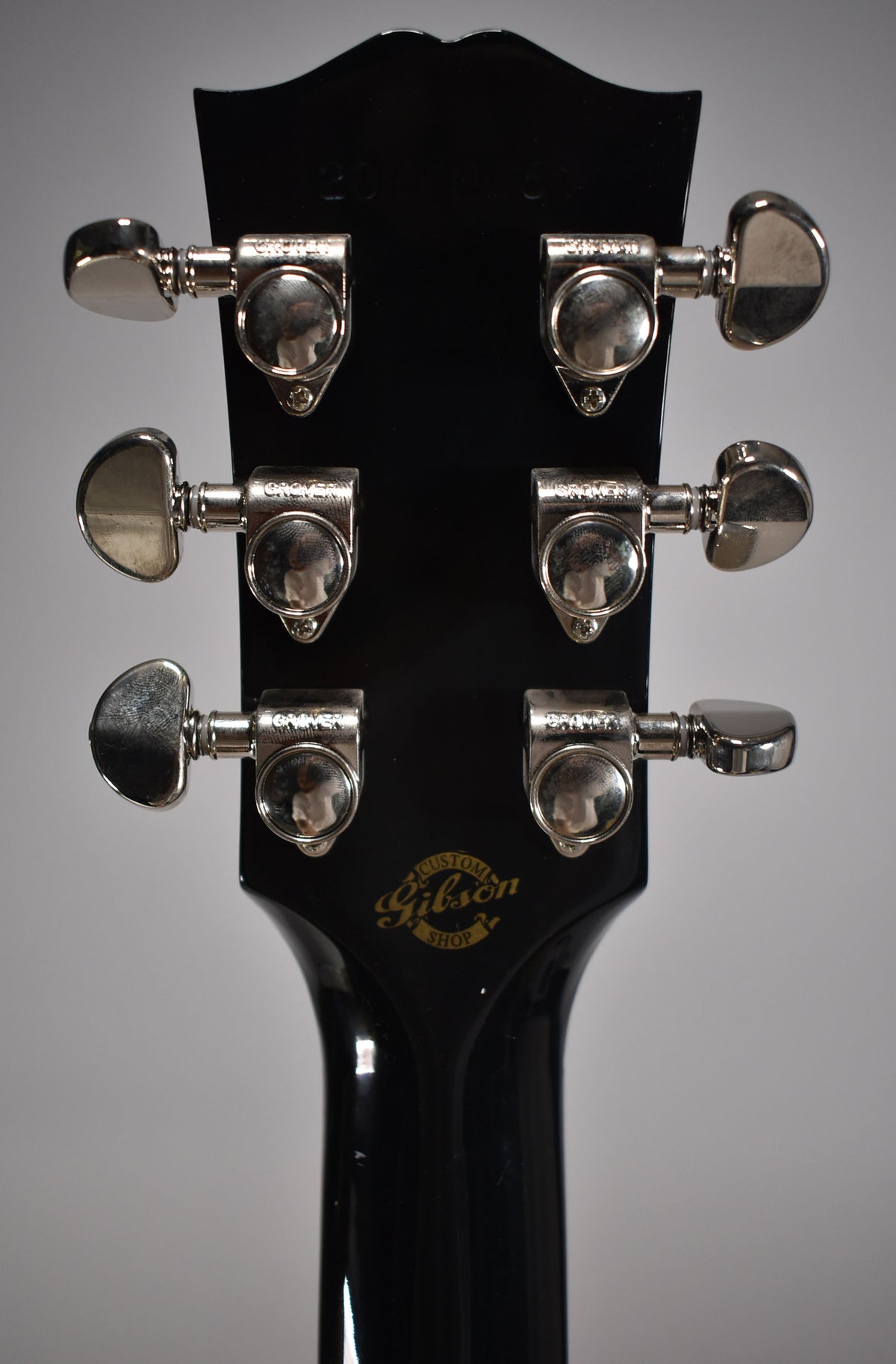 Rear view of the ebony headstock and neck, showing six chrome tuners with kidney-shaped buttons and a gold Custom Shop logo.