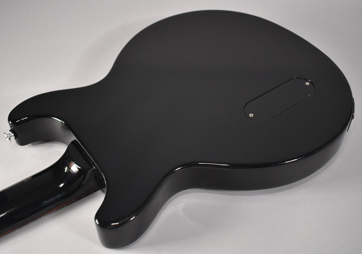 The back of an ebony Les Paul Junior Double Cut, showing the control cavity cover, neck joint, and lower strap button.