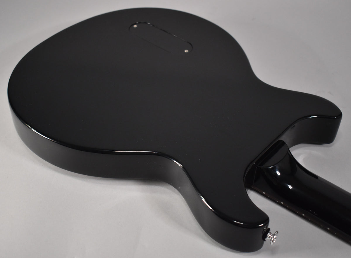 The back of the guitar's glossy black body and neck, with a control cavity cover and strap button visible.