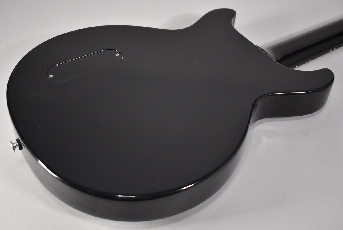 The back of a black double-cutaway electric guitar, showing a matte finish body with a glossy edge and a black control cavity cover.