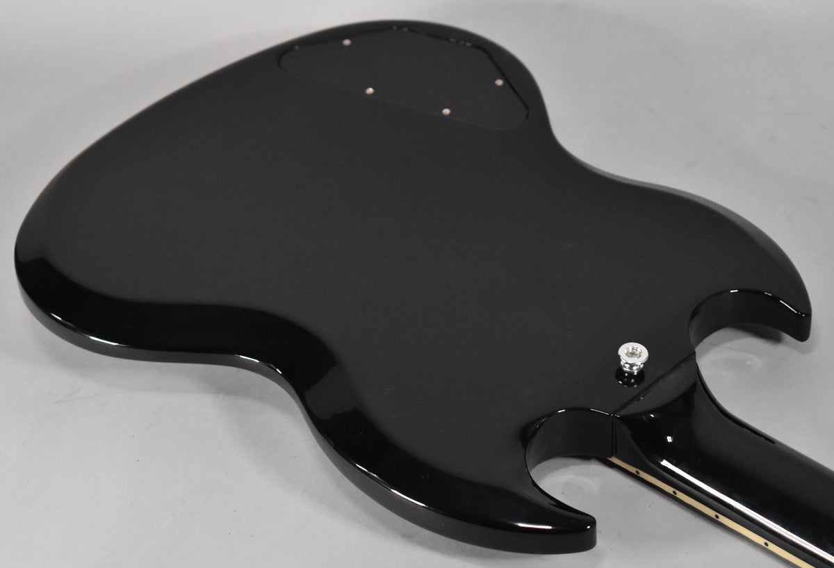 The back of a glossy black SG guitar, angled from the lower bout towards the upper horn, showing the control cavity cover.
