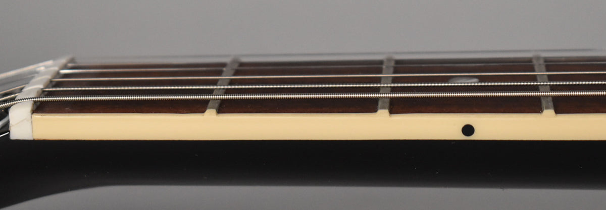 Close-up of the guitar's fretboard from the side, showing the nut, frets, strings, and a black side dot marker.