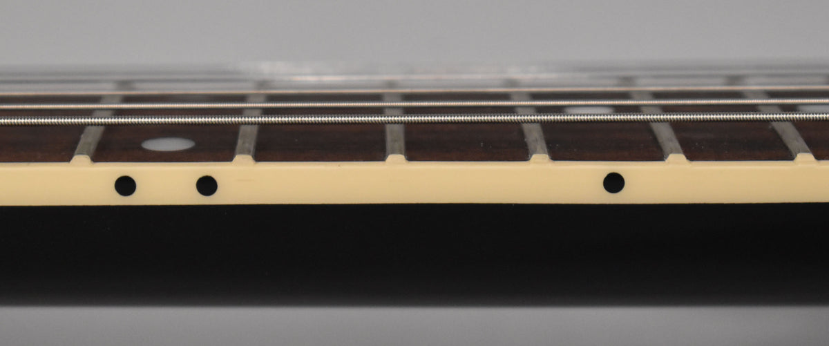 Close-up of the guitar's ebony fretboard and cream binding, showing fret markers and side dots from a low, angled perspective.