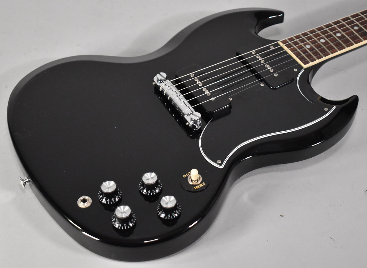 The black SG Special's body is angled from the lower left, showing the chrome bridge, black P90 pickups, and four control knobs.