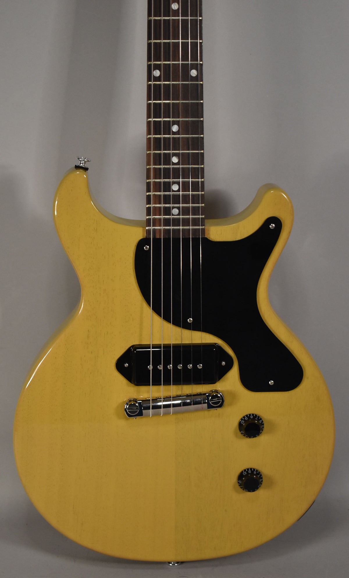 The TV Yellow double-cutaway body and neck of the guitar are shown from the upper bout, with a black pickguard and P90 pickup.