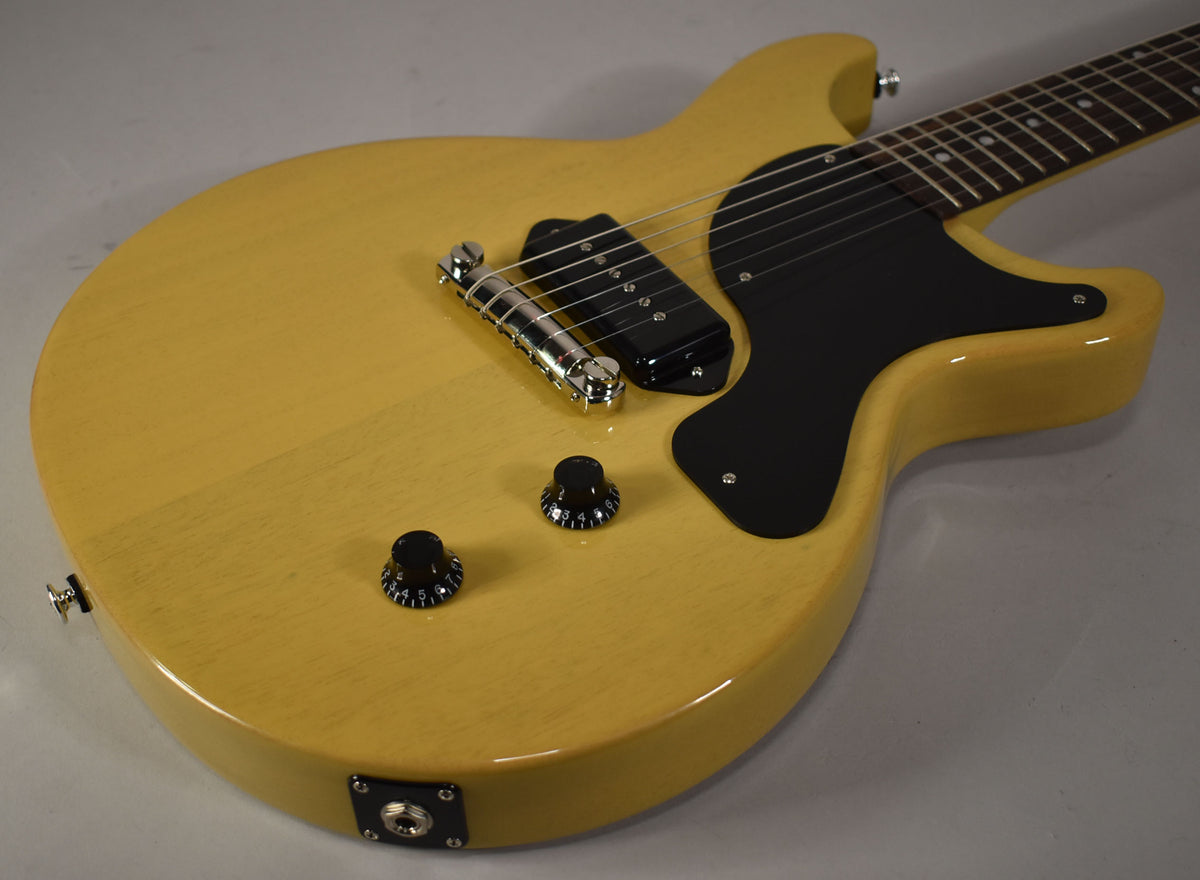 Upper body of a TV Yellow double-cut guitar, showing a black pickguard, P90 pickup, chrome bridge, and two black control knobs.