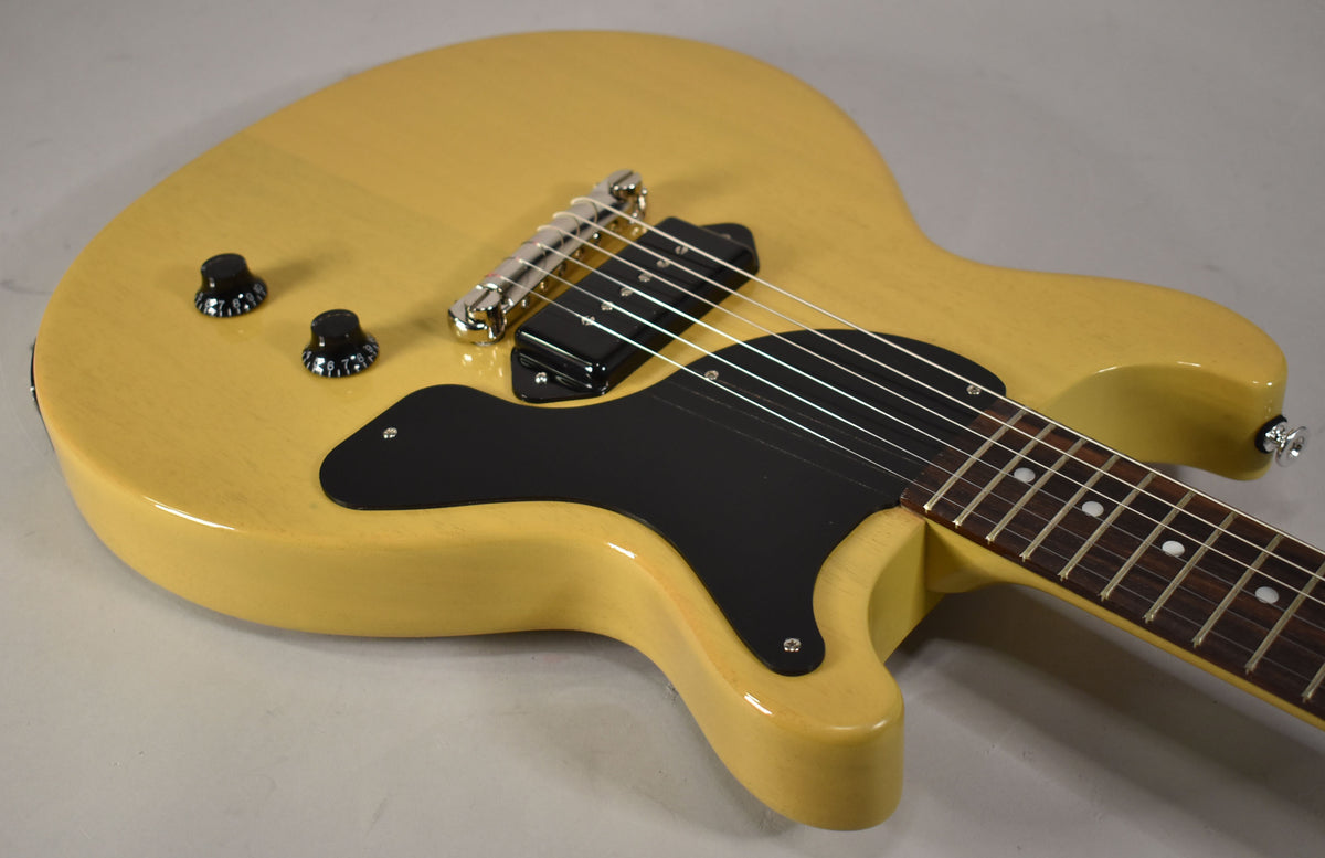 Upper body of a TV Yellow double-cut guitar, showing the black pickguard, P90 pickup, two black control knobs, and chrome bridge.