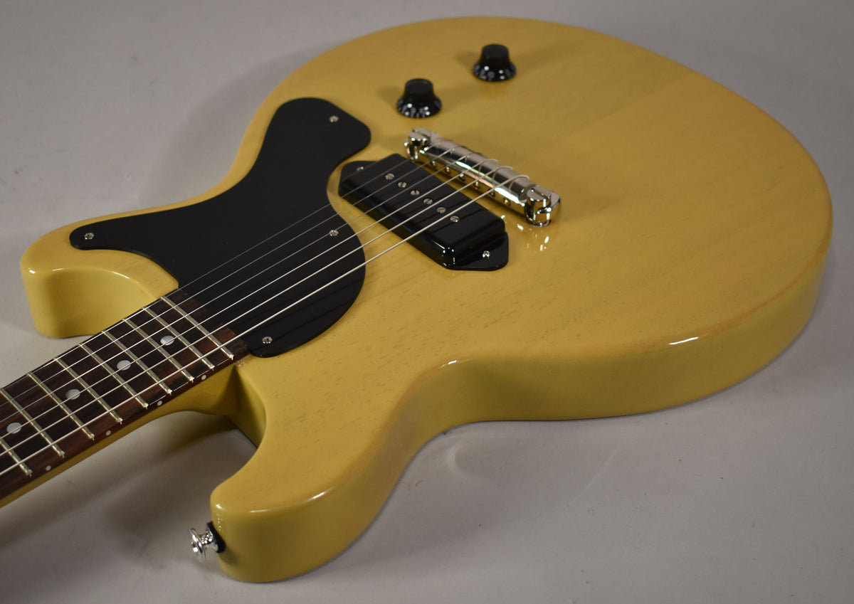 The TV Yellow double-cut guitar body is angled, showing the black pickguard, P90 pickup, chrome wraparound bridge, and two black knobs.