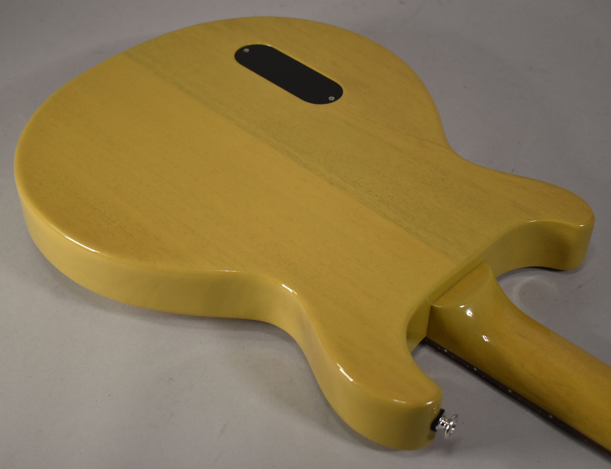The back of the TV Yellow guitar body and neck, showing the control cavity cover and a chrome strap button.