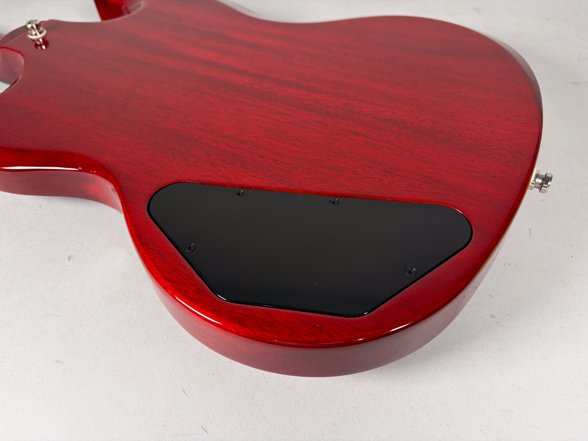 The back of a cherry red bass body, showing the grain, a black control cavity cover, and a strap button.