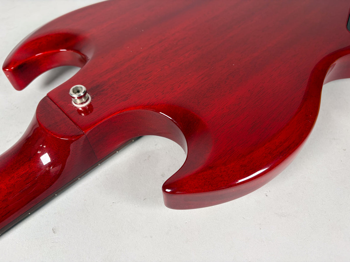 Close-up of the cherry red SG bass body and neck joint, showing the output jack and the lower horn's curve.