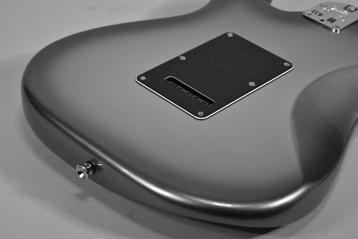 The back of a metallic gray electric guitar, showing the tremolo spring cover and output jack.