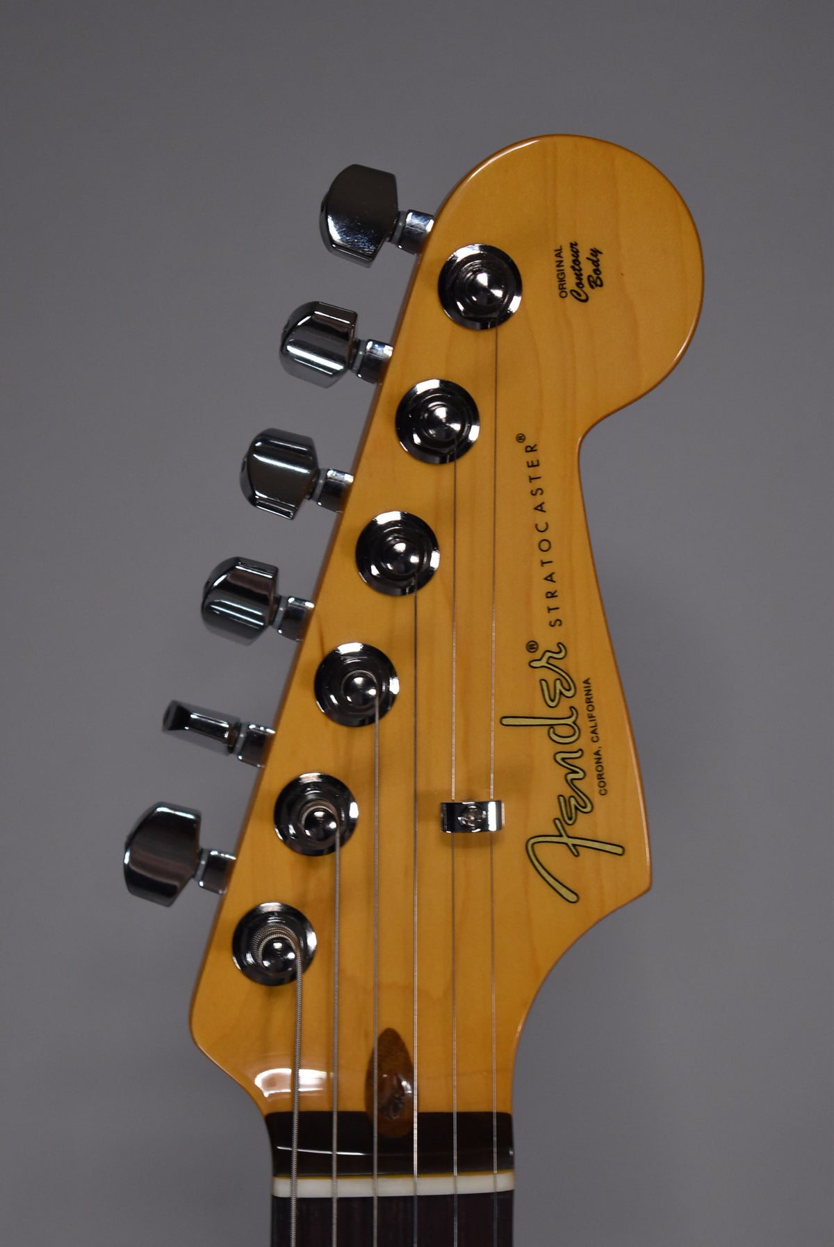Close-up of the guitar's headstock, angled slightly left, showing six chrome tuners and a light wood finish with no visible wear.