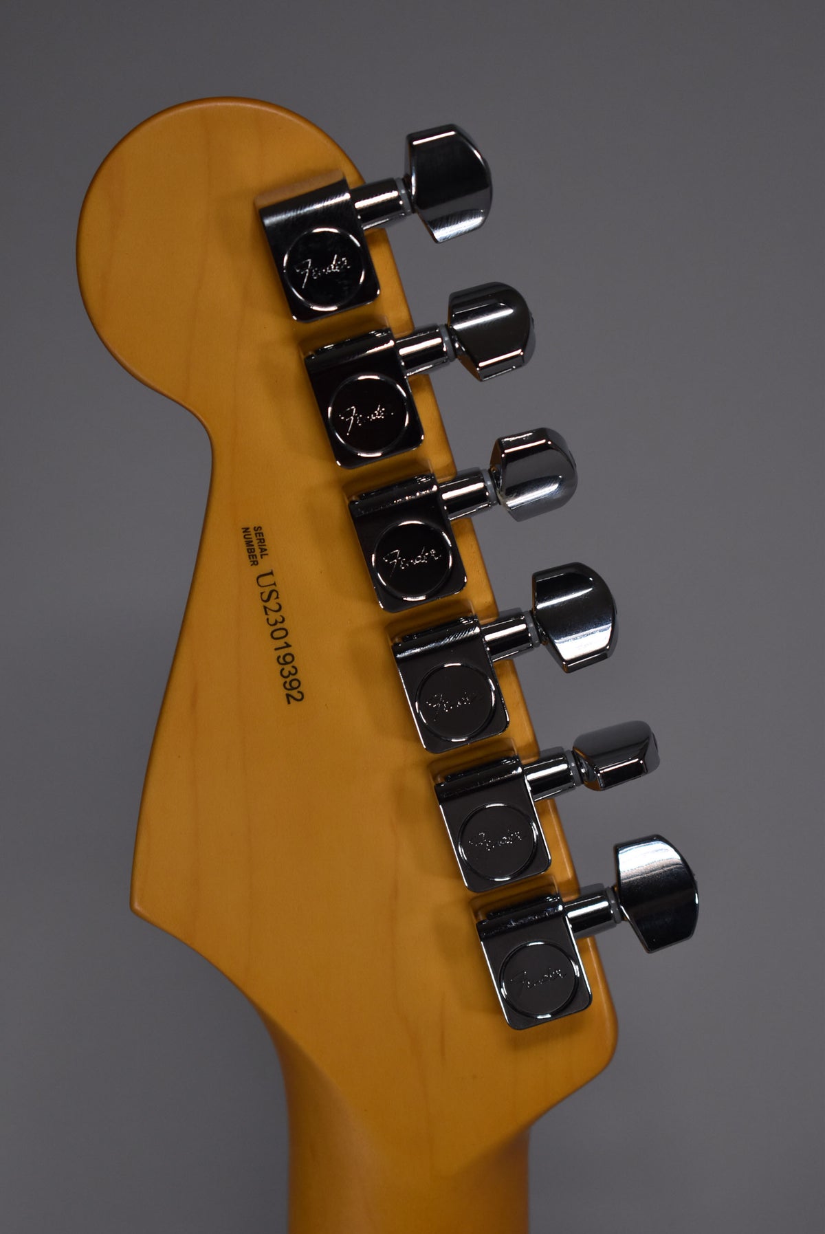 Rear view of the Stratocaster's light-colored headstock and neck, showing six chrome tuning machines and a serial number.