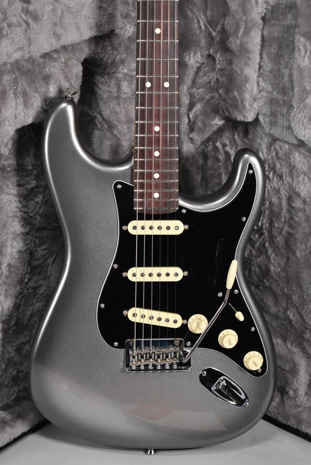 A metallic silver Stratocaster with a dark fretboard, black pickguard, cream pickups, and matching control knobs.