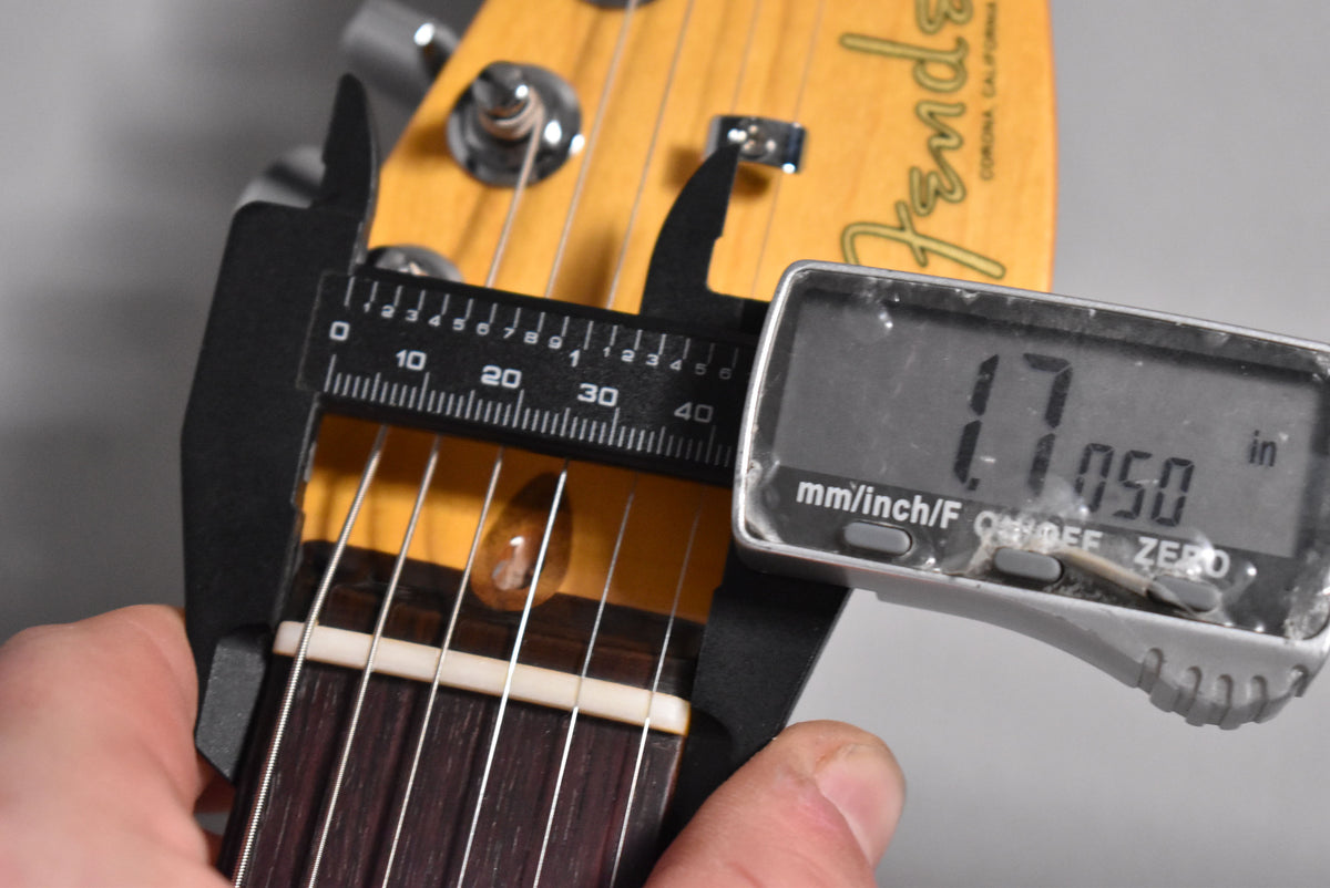 Close-up of the guitar's headstock and nut, with a digital caliper measuring the nut width at 1.77 inches.