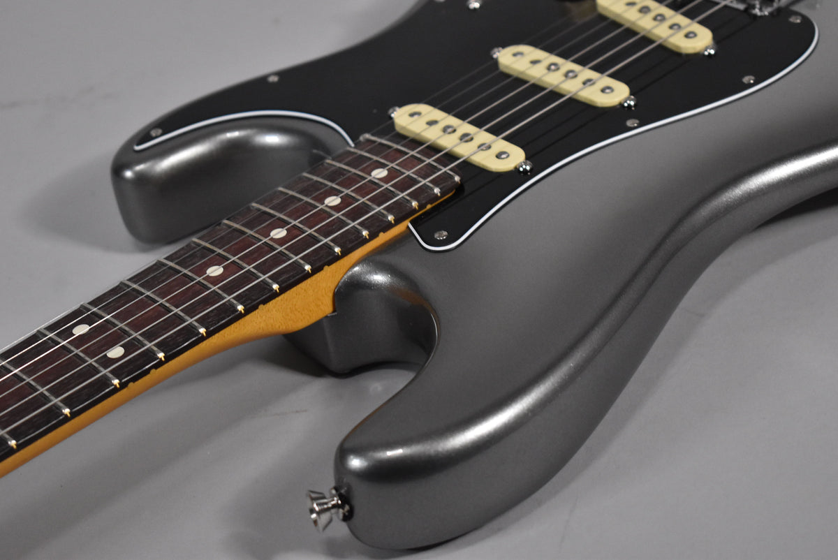The guitar's metallic gray body and black pickguard are visible from the lower bout, with three cream single-coil pickups.