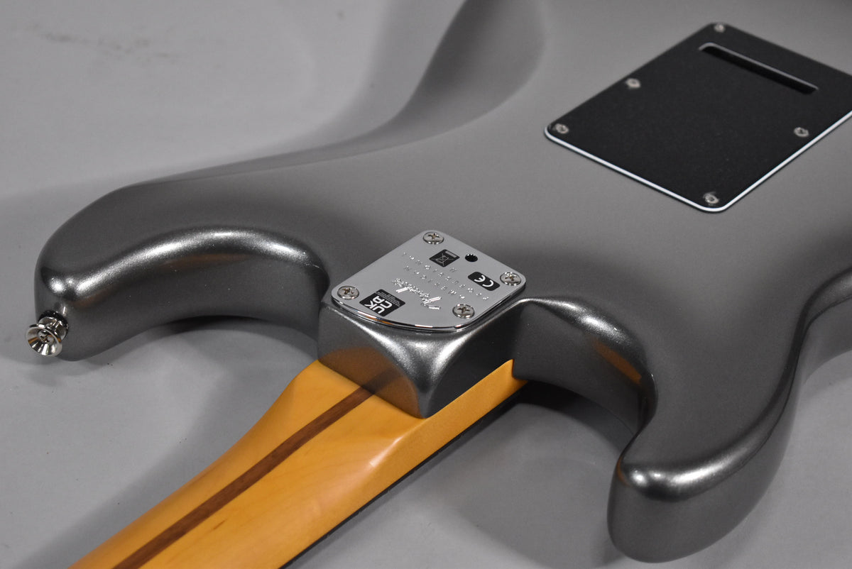 The guitar's metallic gray body, with a visible neck plate and black tremolo cover, is shown from the back, angled right.