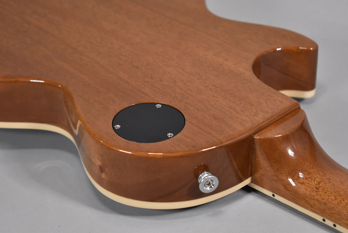The back of the guitar's lower bout and neck heel, showing the mahogany finish, cream binding, and chrome output jack.