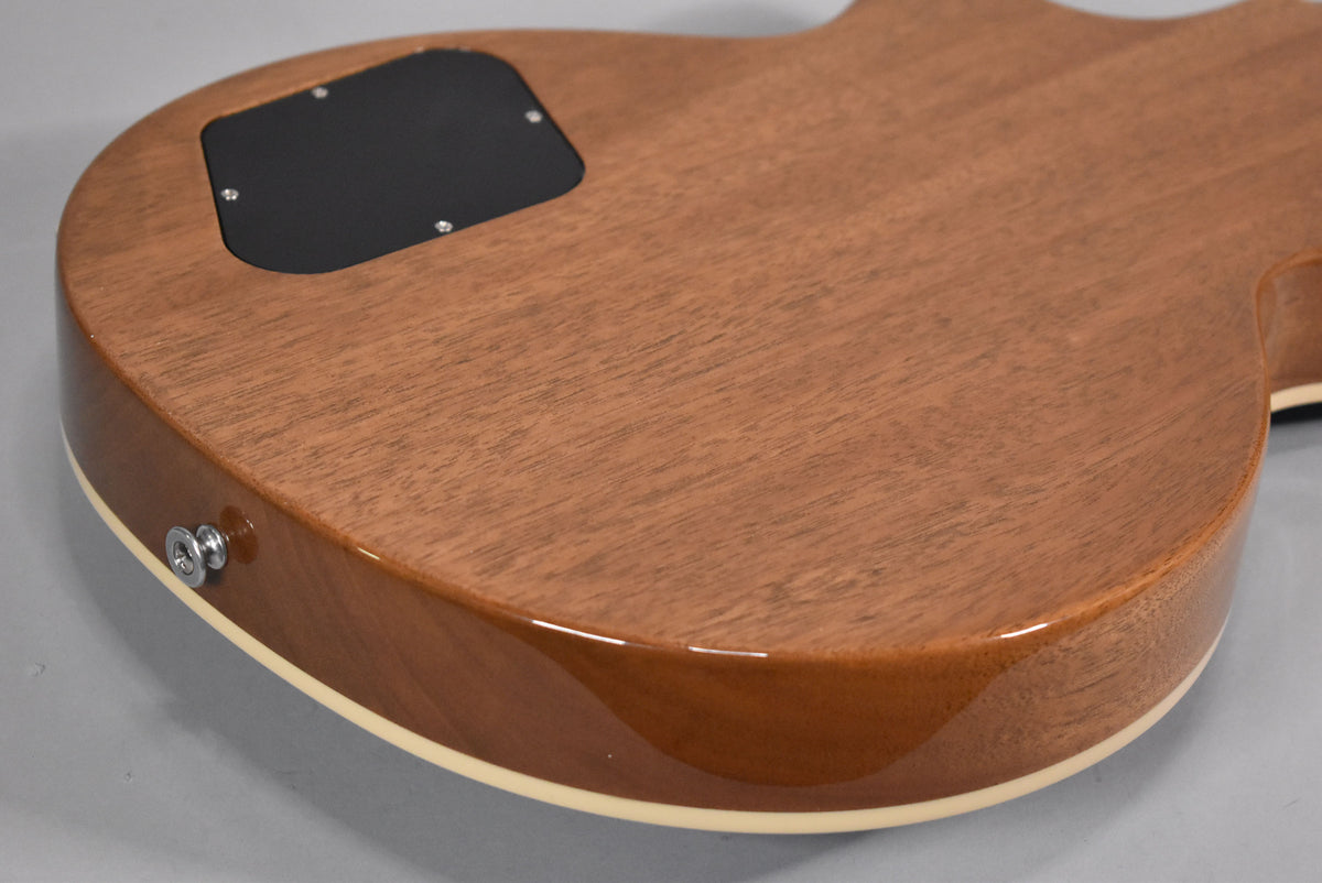 The guitar's back shows a natural wood grain finish with a black control cavity cover and a chrome output jack.