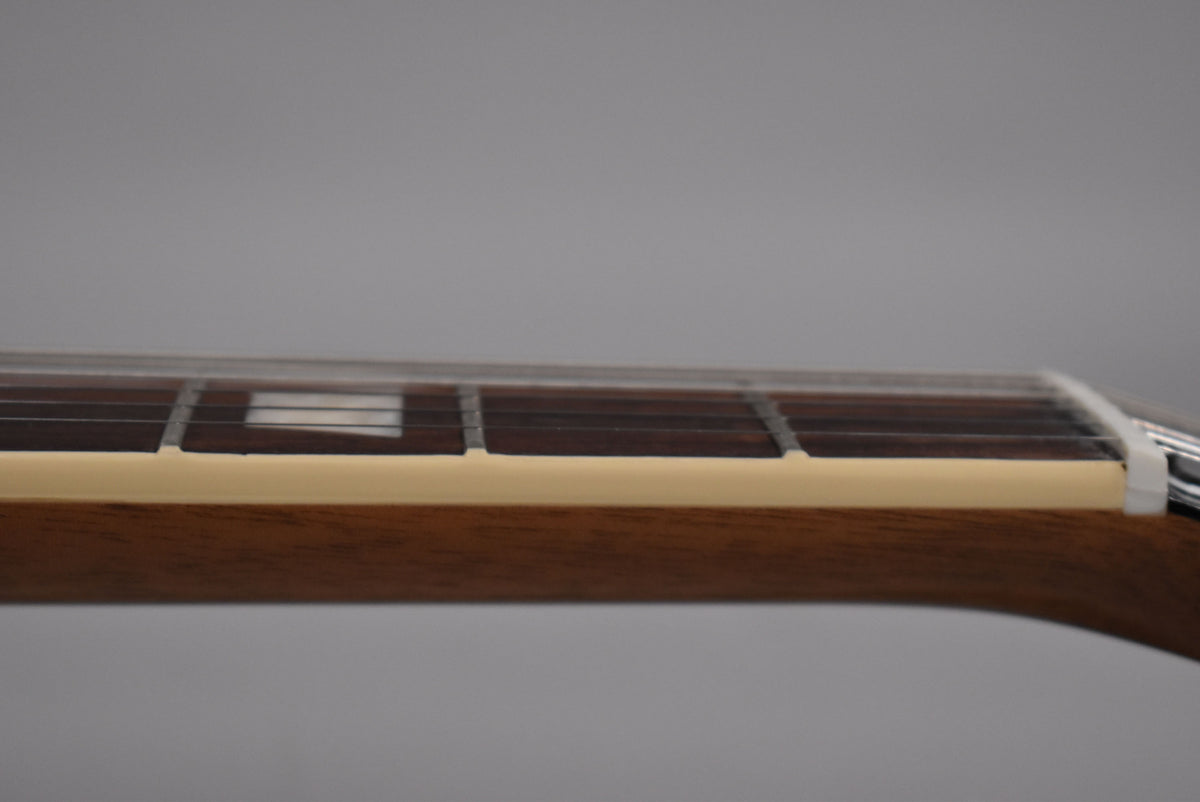 Close-up of the guitar's fretboard and neck from the side, showing dark wood, cream binding, and a white nut.