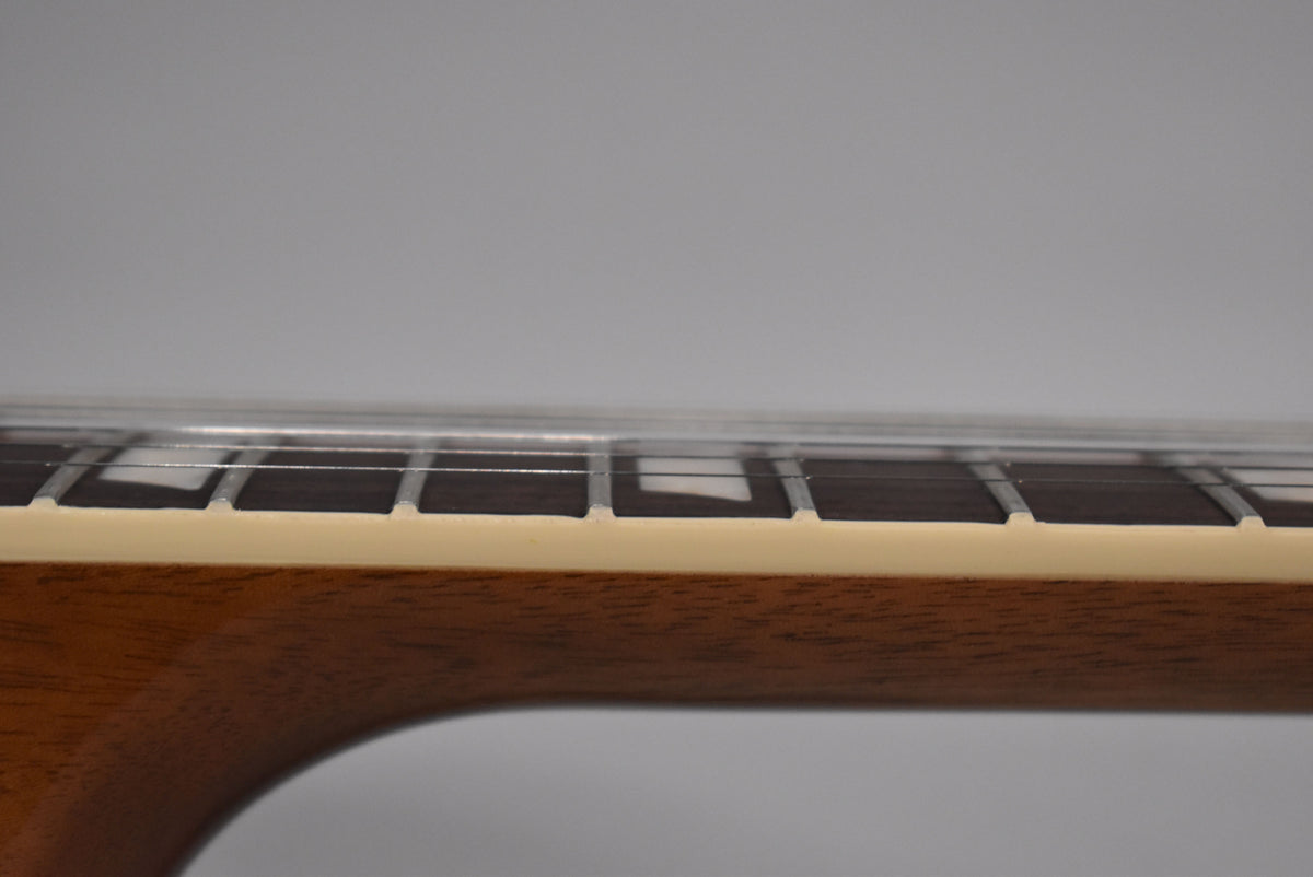 Close-up of the guitar's neck from the side, showing the dark fretboard with trapezoid inlays and cream binding.