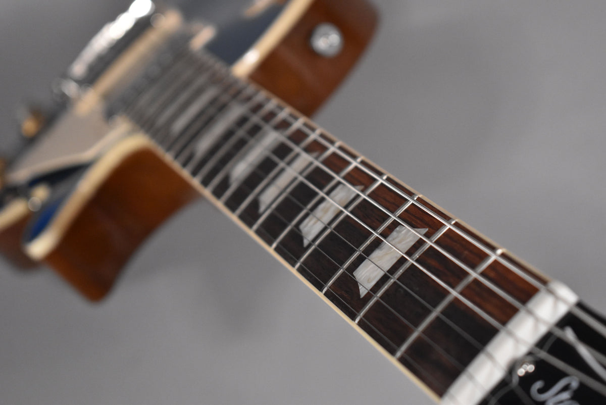 Close-up of the guitar's dark fretboard with trapezoid inlays, showing the frets and strings, angled from the headstock towards the body.