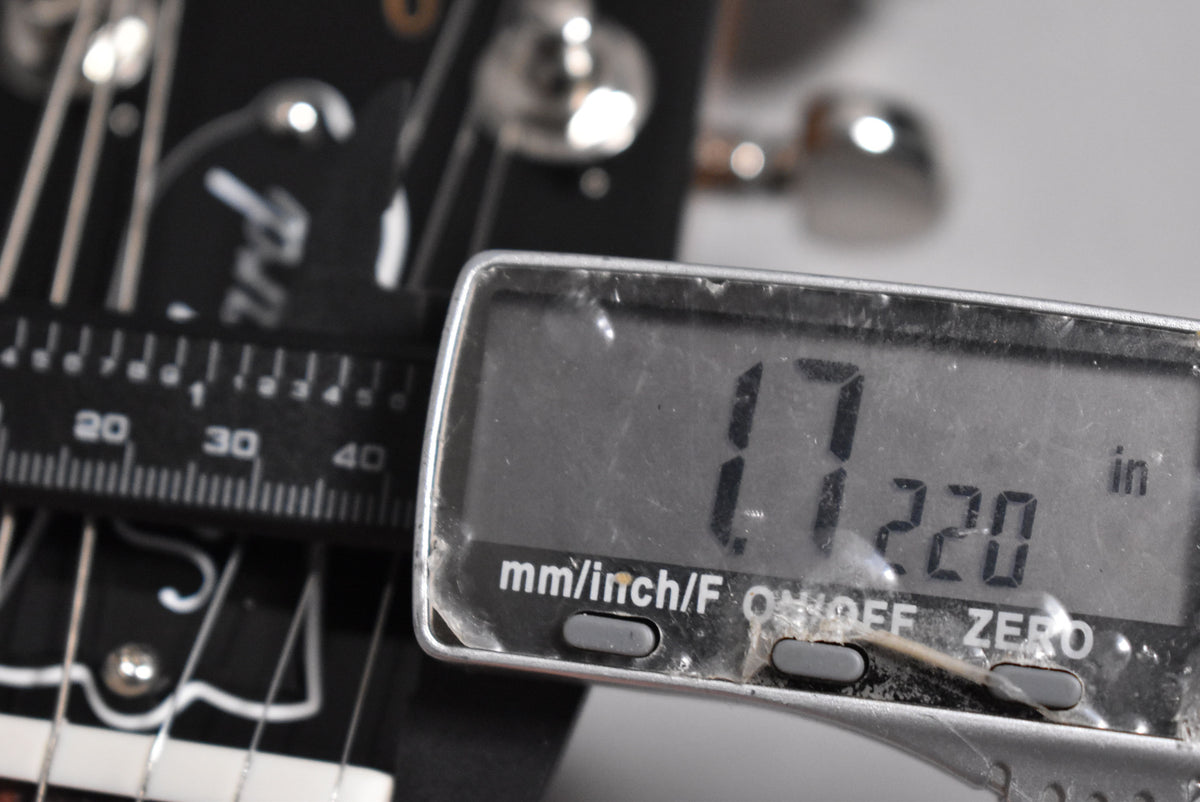 Close-up of the guitar's nut and headstock, with a digital caliper measuring the nut width at 1.7220 inches.