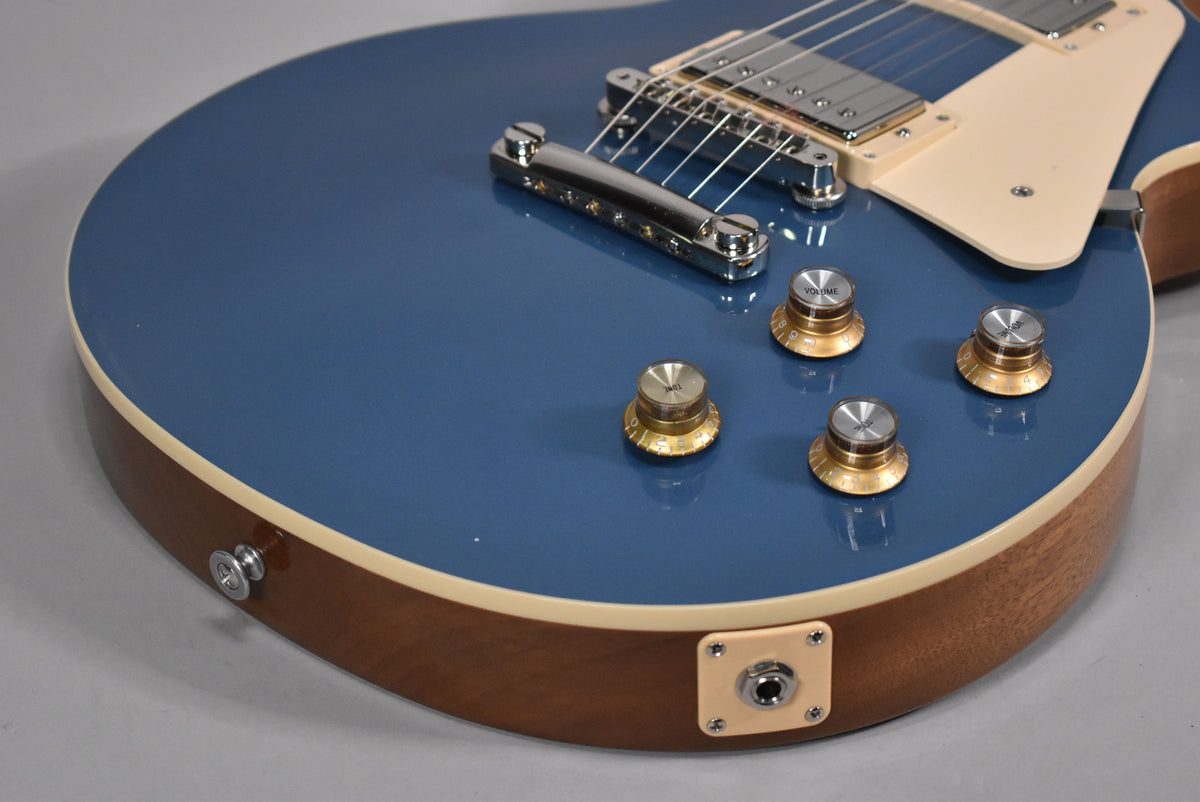 Close-up of the guitar's lower bout, showing the glossy Pelham Blue top, cream binding, mahogany sides, and four gold-capped control knobs.