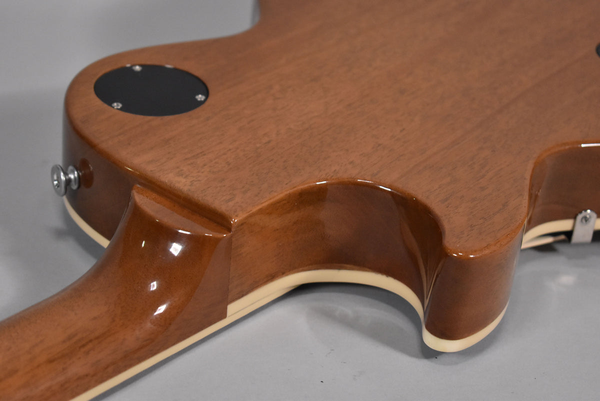 The guitar's back, showing the mahogany body and neck with a glossy finish, cream binding, and a black control cavity cover.