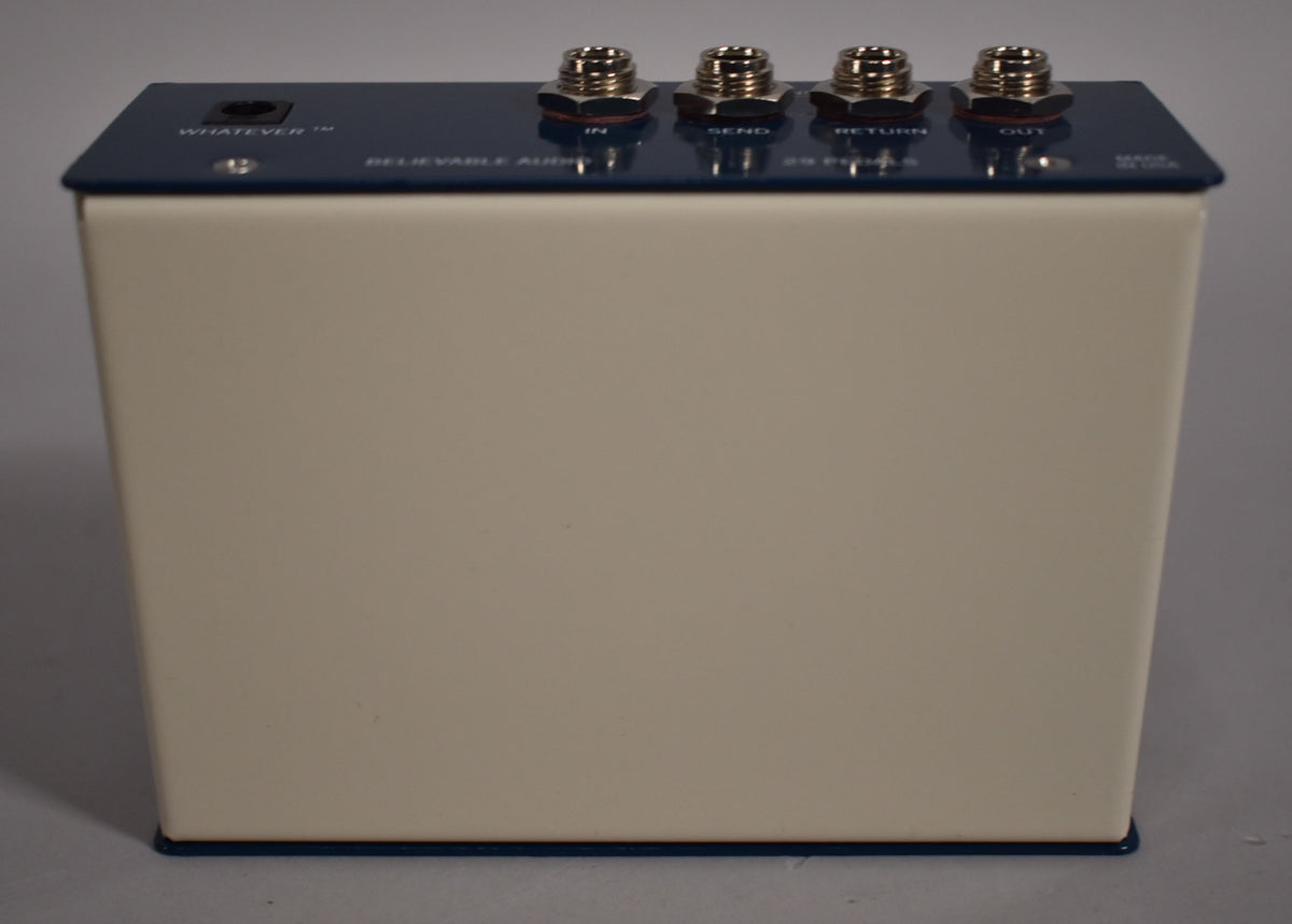 The cream-colored pedal is viewed from the front, with a dark blue top panel featuring a power input and four silver jacks.