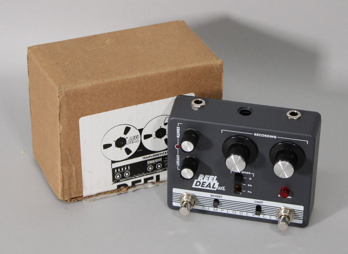The dark grey pedal is angled right, showing its top panel with two large knobs, two smaller knobs, a toggle switch, and two footswitches.