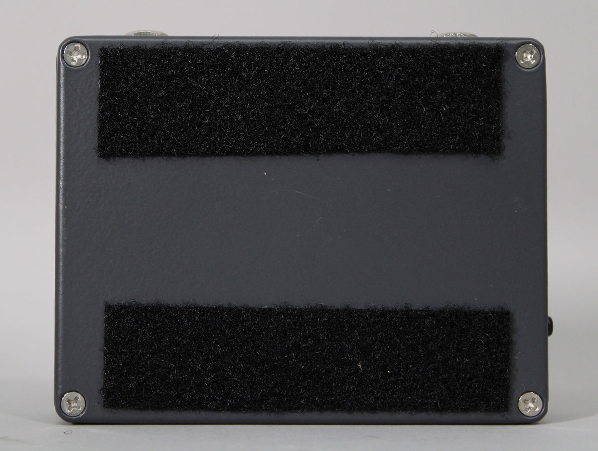 The pedal's dark gray underside is shown, featuring two wide strips of black hook-and-loop fastener and four silver screws.